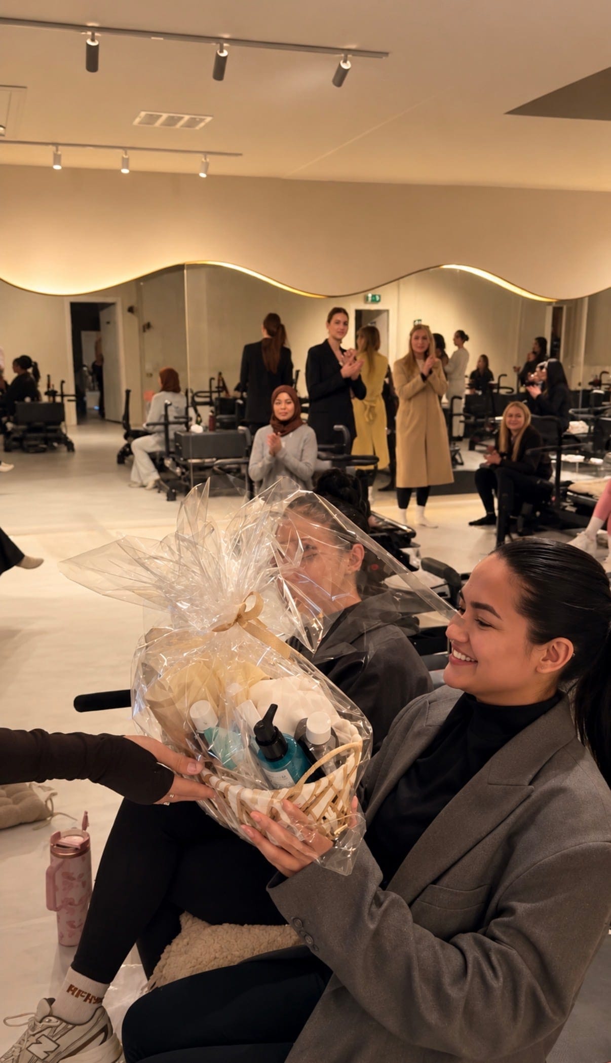 Een gast krijgt bij een ladies night een cadeaumand, terwijl de anderen applaudisseren